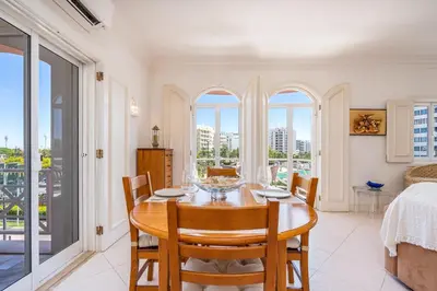 a dining room with a table and chairs and windows at Vilamoura City Centre Flat in Vilamoura