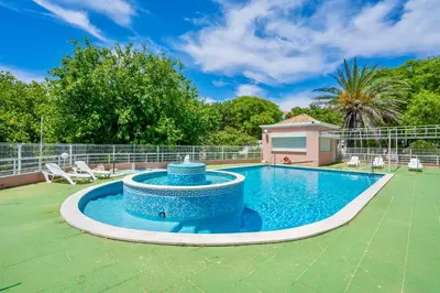 a swimming pool in a yard with chairs around it at Vilamoura City Centre Flat in Vilamoura