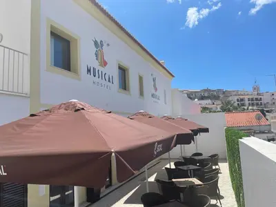 a group of umbrellas and chairs in front of a building at Musical Hostel in Albufeira