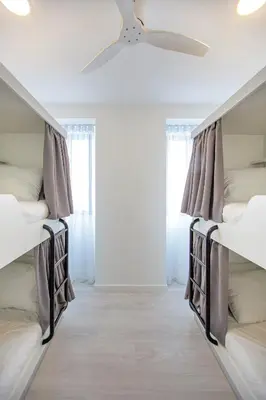 two beds in a room with a ceiling fan at Musical Hostel in Albufeira