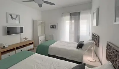 a white bedroom with two beds and a tv at Casa AL Reis in Faro