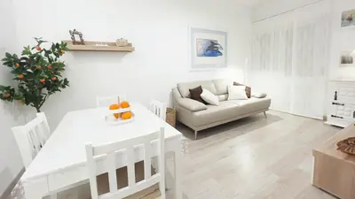 a white living room with a table and a couch at Casa AL Reis in Faro