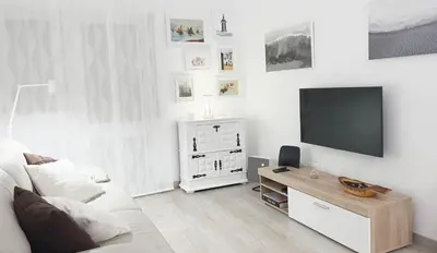a white living room with a tv and a white couch at Casa AL Reis in Faro