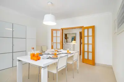 a white dining room with a white table and chairs at WHome Family Holidays w/ S-Pool, AC, Elevator & Garage in Quarteira