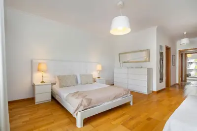 a white bedroom with a bed and a mirror at WHome Family Holidays w/ S-Pool, AC, Elevator & Garage in Quarteira