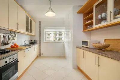 a large kitchen with white cabinets and a window at WHome Family Holidays w/ S-Pool, AC, Elevator & Garage in Quarteira