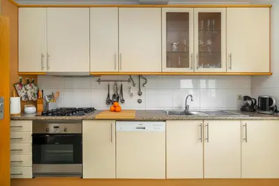a kitchen with white cabinets and a sink at WHome Family Holidays w/ S-Pool, AC, Elevator & Garage in Quarteira