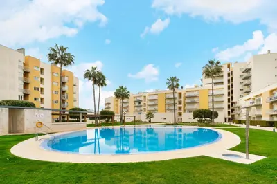 a large swimming pool in front of apartment buildings at WHome Family Holidays w/ S-Pool, AC, Elevator & Garage in Quarteira