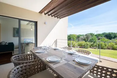 a dining room table with chairs and a large window at Apart L'Orange in Vilamoura