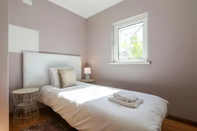 a white bedroom with a bed and a window at Villa Alfazema in Albufeira