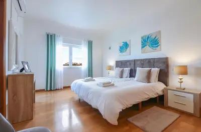 a bedroom with a large bed with white sheets at Villa Alfazema in Albufeira