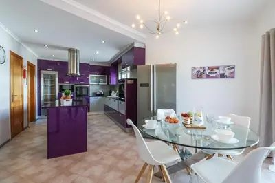 a kitchen and dining room with a glass table and chairs at Villa Alfazema in Albufeira