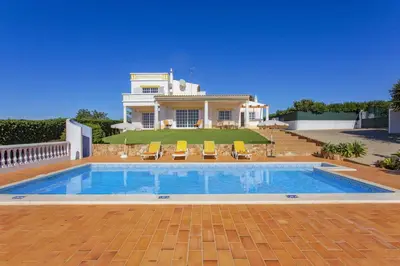 a house with a swimming pool in front of a house at Villa Colina do Sol by Villa Plus in Paderne