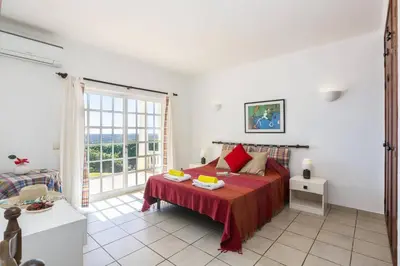a bedroom with a bed and a large window at Villa Colina do Sol by Villa Plus in Paderne
