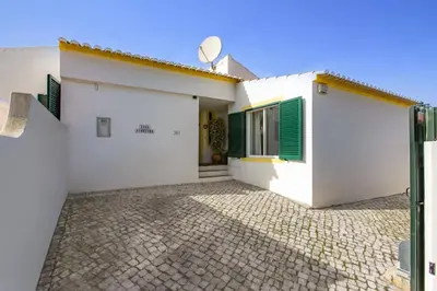 a white house with green shutters and a patio at Villa Pinheiro Oura by Villa Plus in Albufeira