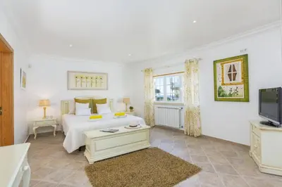 a white bedroom with a bed and a tv at Villa Quinta dos Bicos by Villa Plus in Albufeira