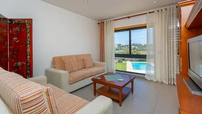 a living room with a couch and a tv at Parque Atlântico Apartment T1 in Quarteira