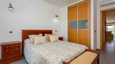 a bedroom with a large bed and a wooden cabinet at Parque Atlântico Apartment T1 in Quarteira
