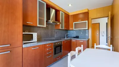 a kitchen with wooden cabinets and a white table at Parque Atlântico Apartment T1 in Quarteira