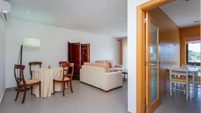a living room and dining room with a table and chairs at Parque Atlântico Apartment T1 in Quarteira