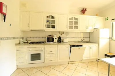 a white kitchen with white cabinets and white appliances at Vilamoura MiraGolf With Pool by Homing in Vilamoura