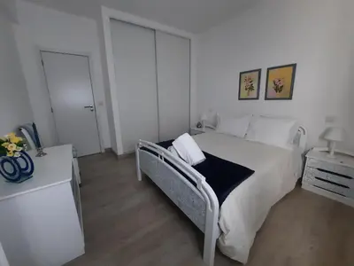 a white bedroom with a bed and a dresser at Casa Cerro Sol in Albufeira