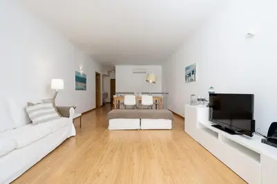 a living room with a white couch and a tv at Apartamento Janelas Oceano - Vilamoura in Quarteira