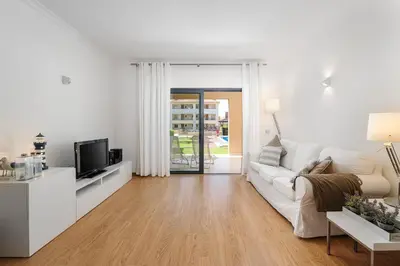 a white living room with a white couch and a tv at Apartamento Janelas Oceano - Vilamoura in Quarteira