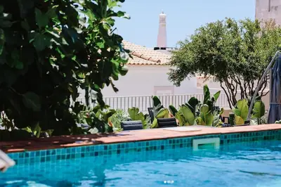 a pool with chairs and trees next to a building at Old Fisherman's Corner 10 - Centro Old Town Albufeira in Albufeira