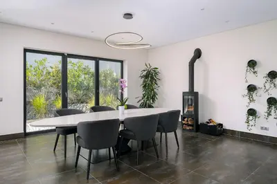 a dining room with a table and chairs and a fireplace at Villa Allegra - Quinta do Lago in Almancil