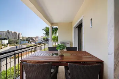 a wooden table and chairs on a balcony with a view at Varandas do Sol - Olhos de Água in Albufeira