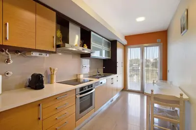 a kitchen with wooden cabinets and a large window at Varandas do Sol - Olhos de Água in Albufeira