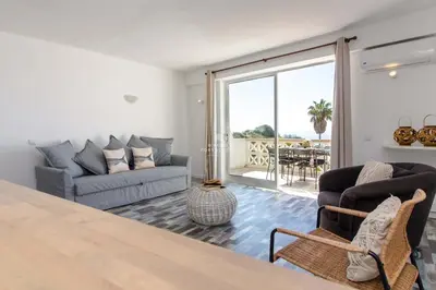 a living room with two couches and a balcony at Aveiros Beach Apartment Ocean View - By Dalma Portuguesa in Albufeira
