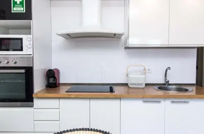 a white kitchen with a sink and a microwave at Aveiros Beach Apartment Ocean View - By Dalma Portuguesa in Albufeira