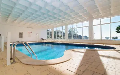 a swimming pool in a large building with windows at Aveiros Beach Apartment Ocean View - By Dalma Portuguesa in Albufeira