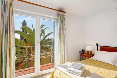 a bedroom with a bed and a large window at Apartamento São Rafael in Albufeira
