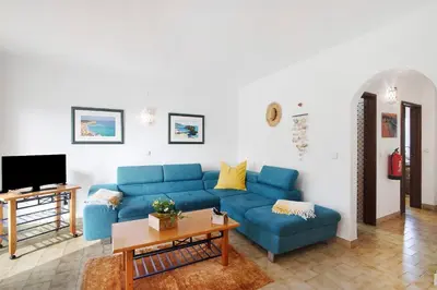 a living room with a blue couch and a tv at Apartamento São Rafael in Albufeira