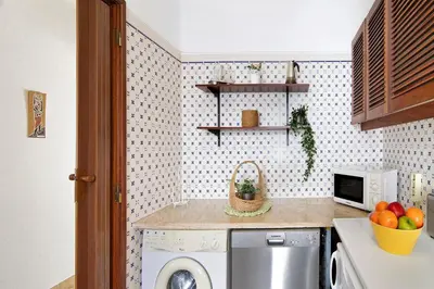 a laundry room with a washing machine and a microwave at Apartamento São Rafael in Albufeira