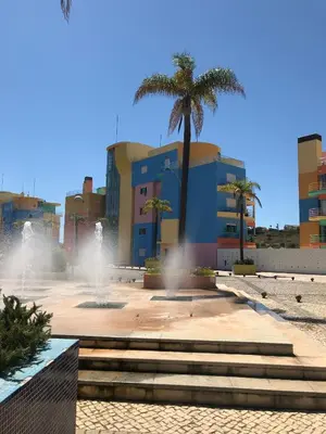 a building with a palm tree and a fountain at Marina View Apartment in Albufeira