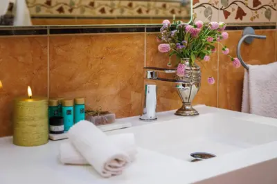 a bathroom sink with a vase of flowers and a candle at Villa Tranberg Suites in Ferreiras