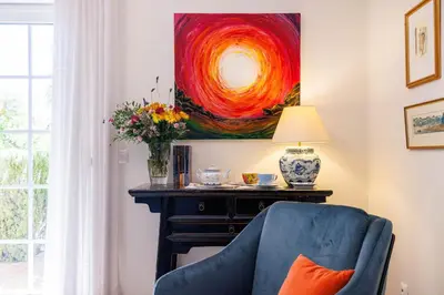 a living room with a blue chair and a painting at Villa Tranberg Suites in Ferreiras