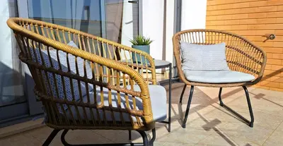 two wicker chairs and a table on a porch at Sul House in Albufeira