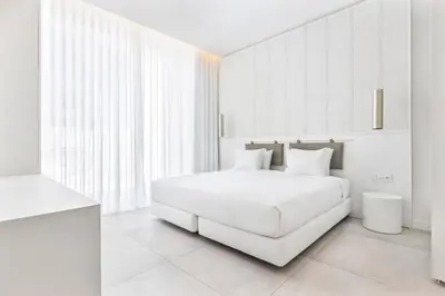 a white bedroom with a white bed and a window at Vila Maria Hotel - Adults Only in Albufeira
