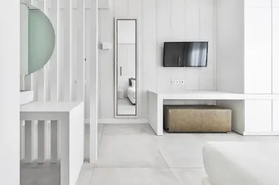 a white bathroom with a toilet and a tv on the wall at Vila Maria Hotel - Adults Only in Albufeira