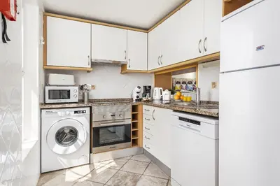 a kitchen with white cabinets and a washer and dryer at Vista Portuguesa by OCvillas in Albufeira
