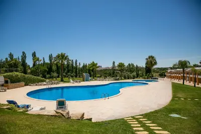 a large swimming pool in a resort with chairs and trees at Villa facing the pool by Algarve Dream Holidays in Fontainhas