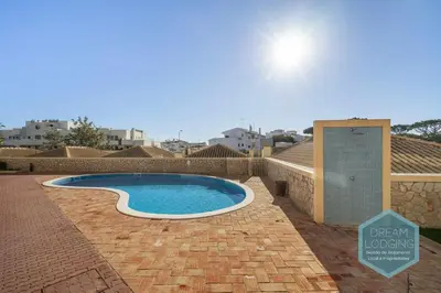 a swimming pool in a brick yard with a sign at Oceanus Jardim - Dream Lodging in Albufeira