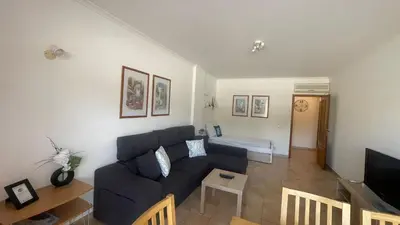 a living room with a blue couch and a tv at Albufeira Apartment Pool & Tennis in Albufeira