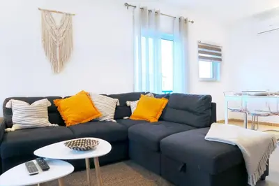 a living room with a blue couch with yellow pillows at Albufeira Central Apartment, 10 mins walk to beach in Albufeira