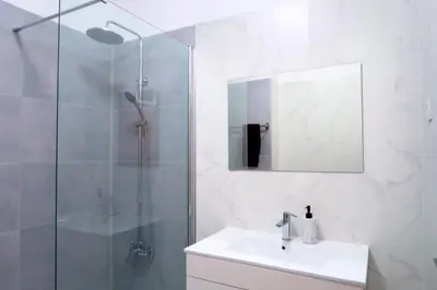 a bathroom with a sink and a shower with a mirror at Albufeira Central Apartment, 10 mins walk to beach in Albufeira